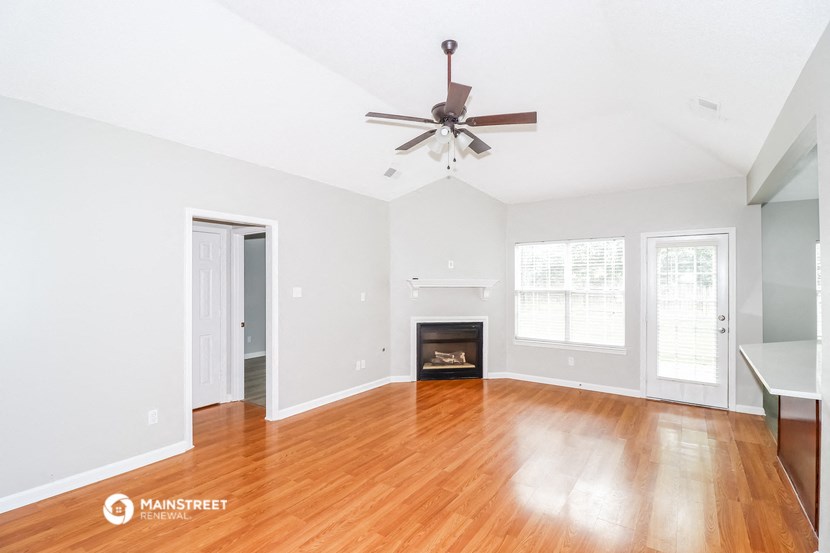 an empty living room with a ceiling fan and a fireplace