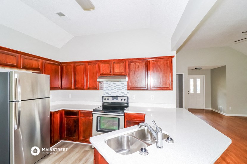 an empty kitchen with wooden cabinets and a stainless steel refrigerator