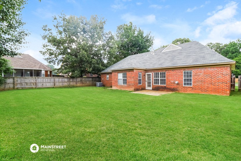 a backyard with a brick house and a fence