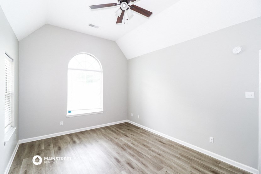 an empty room with white walls and a ceiling fan