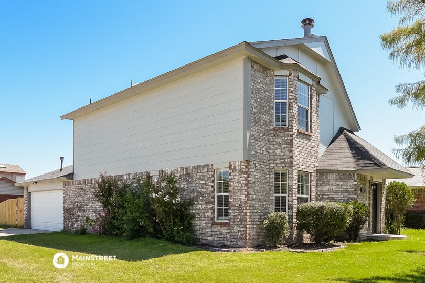 a stone house with a white and gray roof and a lawn