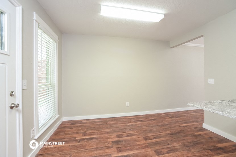 an empty living room with wood flooring and a window