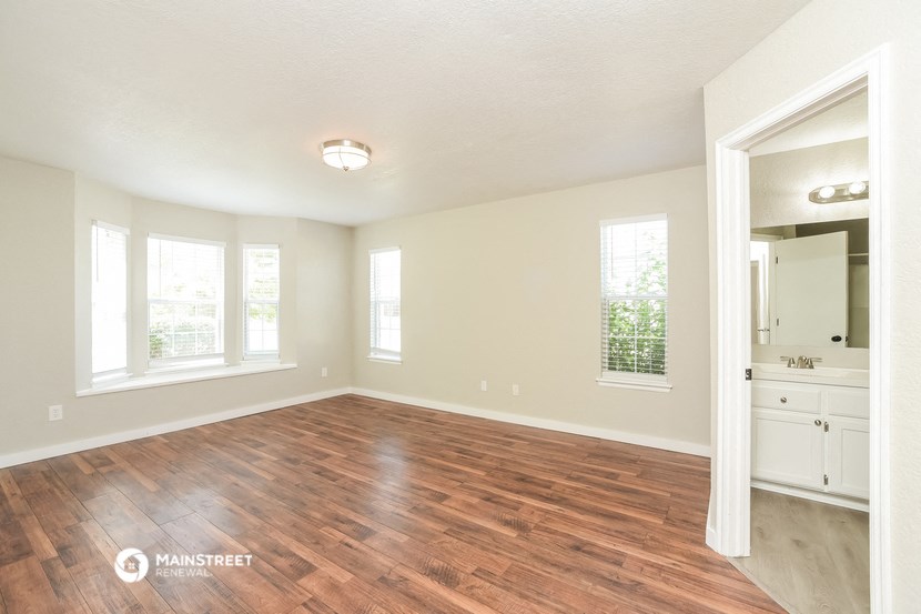 an empty living room with wood flooring and a large mirror