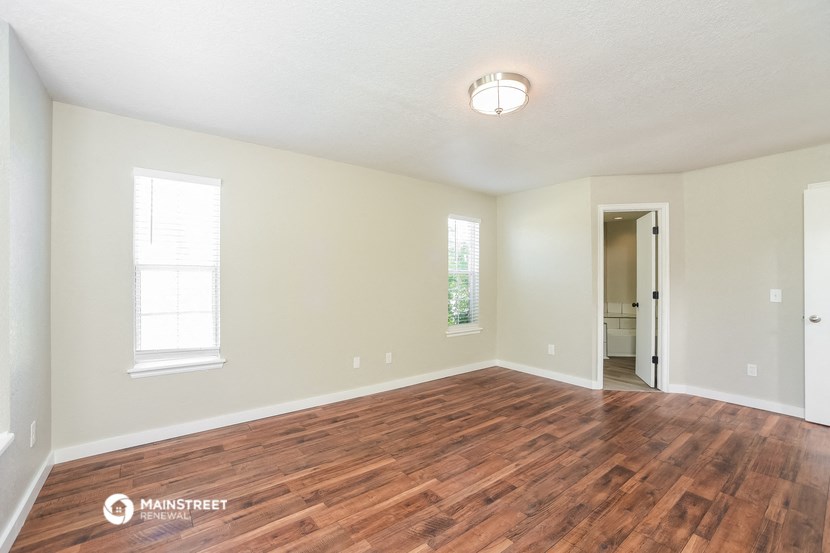 the spacious living room with hardwood flooring and white walls