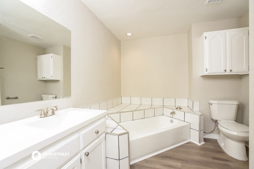 a white bathroom with a tub and a sink and a toilet