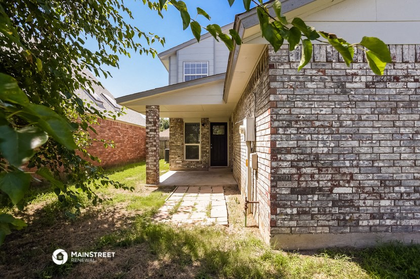 the front of a brick house with a walkway and a tree