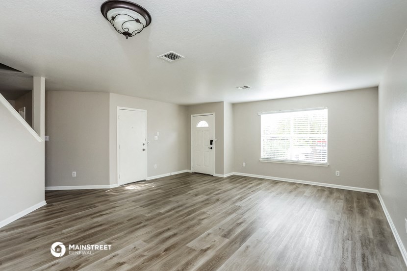 the living room and dining room of an empty house with wood flooring
