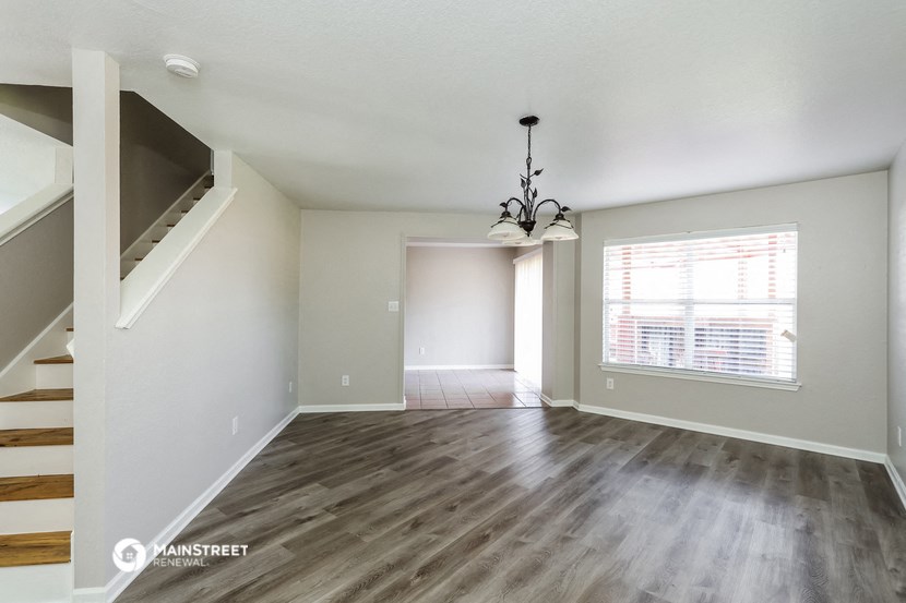 an empty living room with a large window and wood flooring