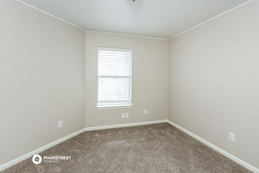 a carpeted room with a window and white walls