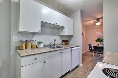 A kitchen with white cabinets and a countertop with a sink and a stove.