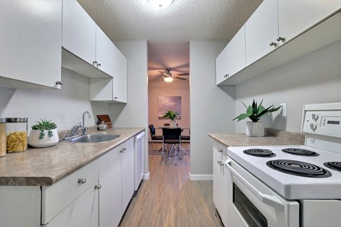 A kitchen with white cabinets and a white stove top oven.