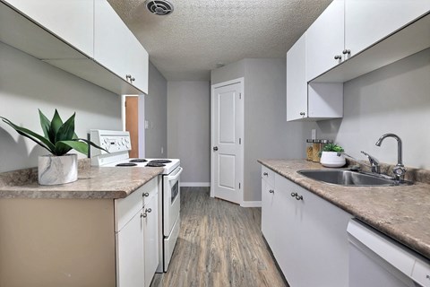 A kitchen with white cabinets and a wooden floor.