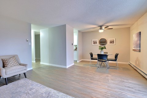 A living room with a chair, a table and a fan.