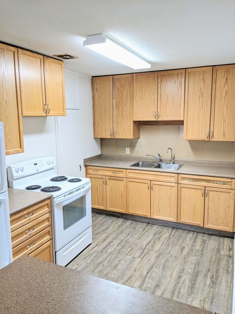 an empty kitchen with wooden cabinets and white appliances
