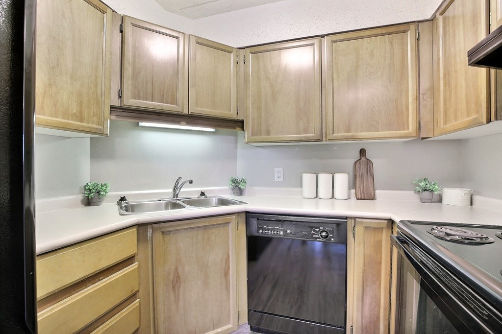 an empty kitchen with wooden cabinets and a black dishwasher