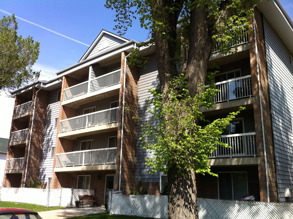 an apartment building with balconies and a tree in front