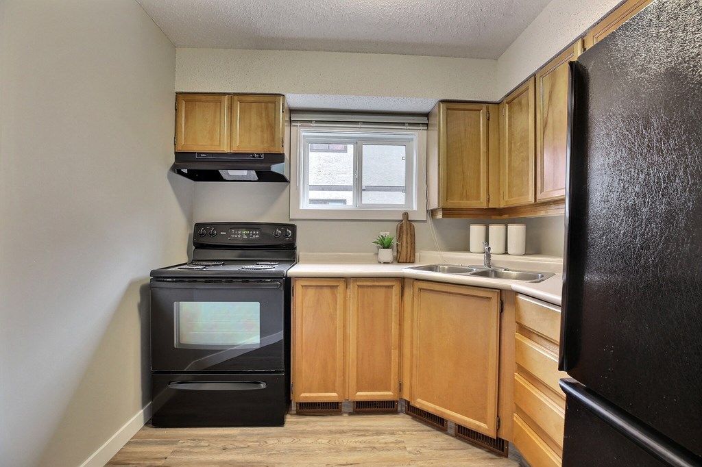 an empty kitchen with wooden cabinets and black appliances