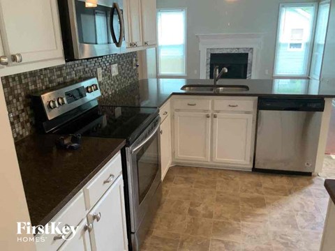 a kitchen with white cabinets and black counter tops