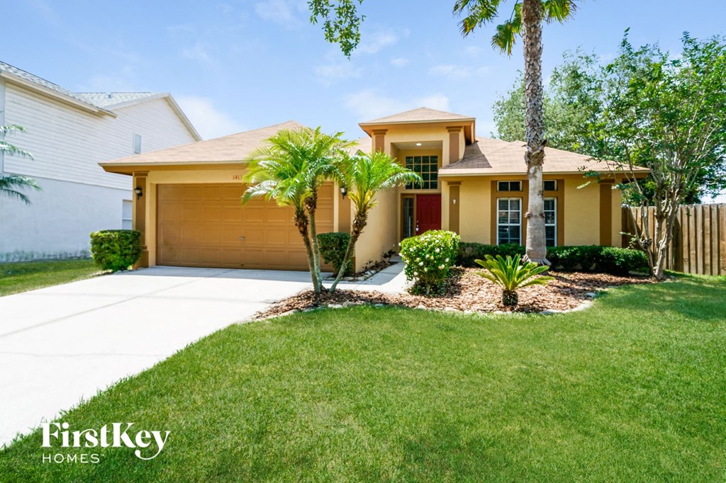 a yellow house with palm trees in the front yard