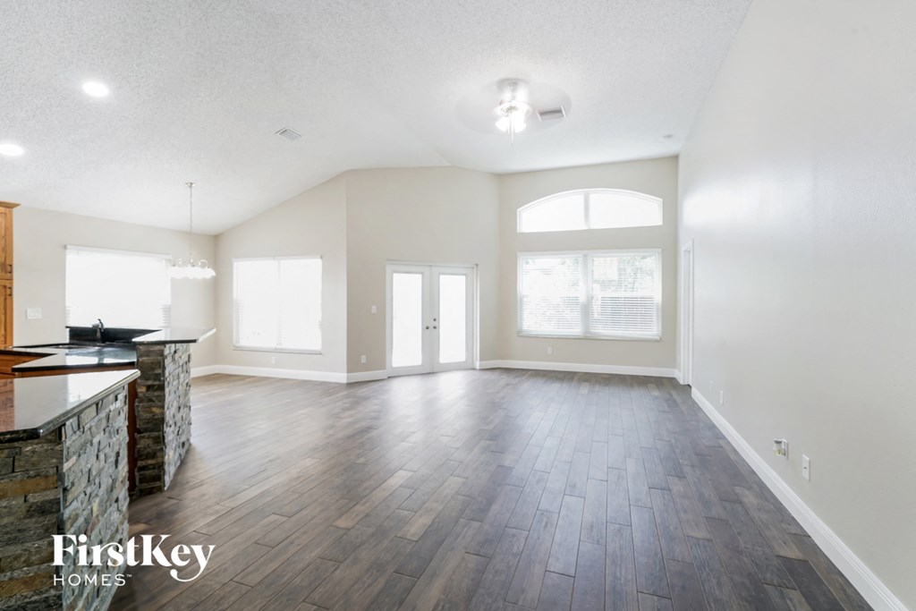 an empty living room and kitchen with wood flooring and a large window