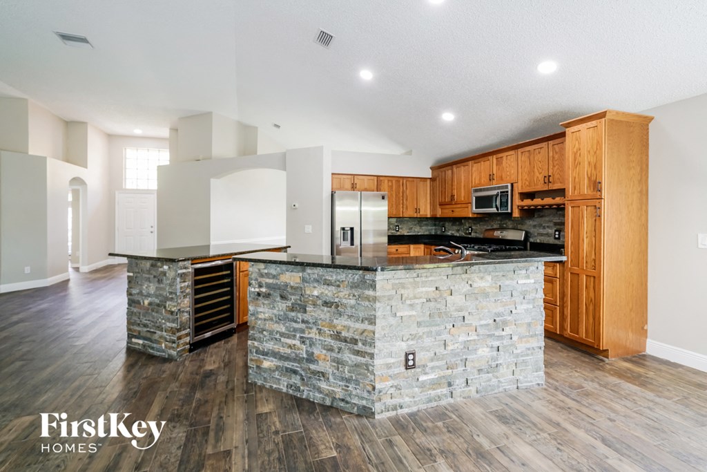 a kitchen with a stone island and wooden cabinets