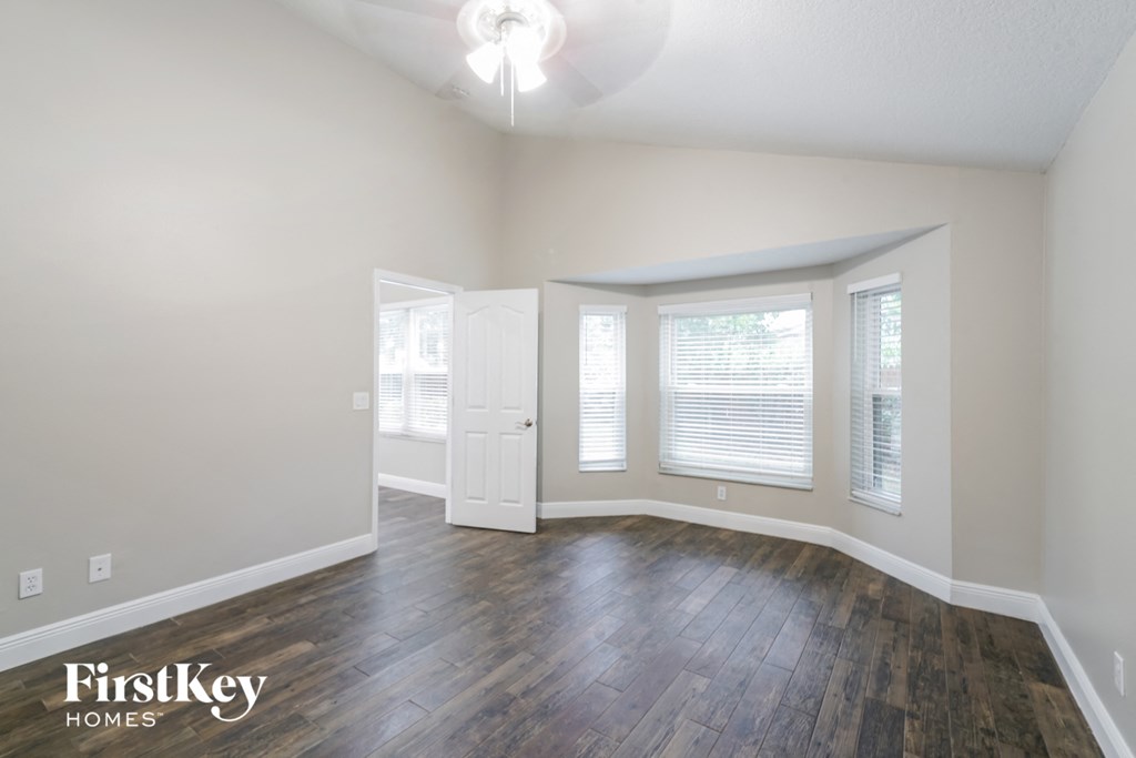 the living room of an empty house with wood flooring and a white door