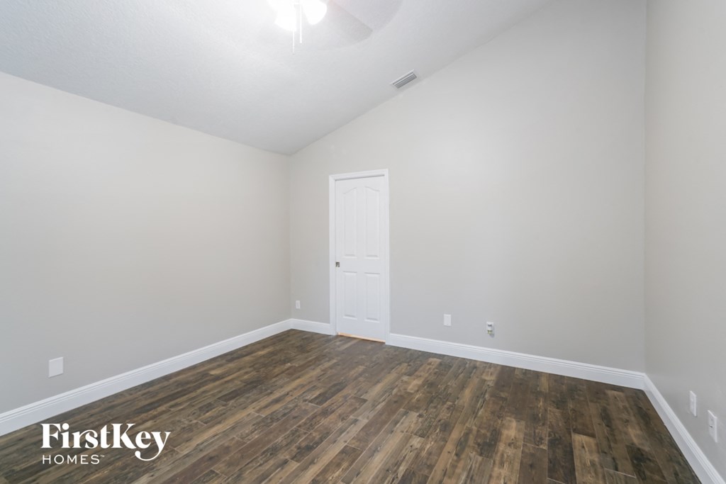 a bedroom with white walls and wood flooring and a white door