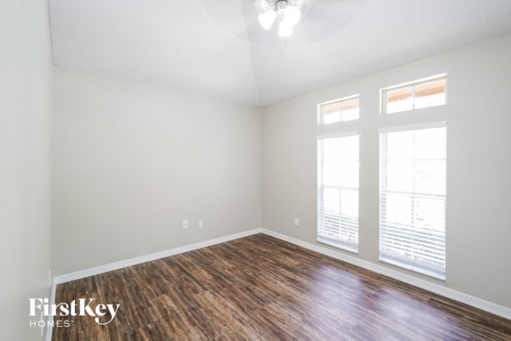 the spacious living room with hardwood flooring and two windows
