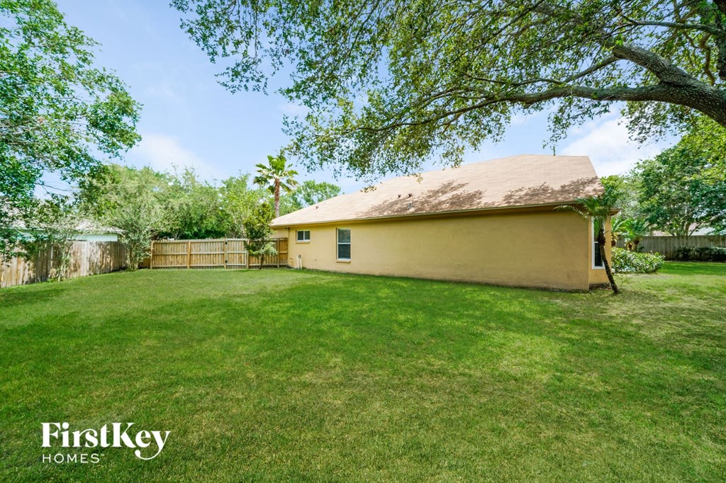 a backyard with a yellow house and a tree