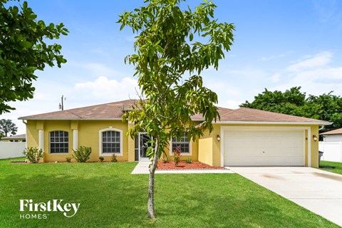 a yellow house with a tree in the yard