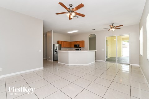 an open kitchen and living room with tile flooring and a ceiling fan