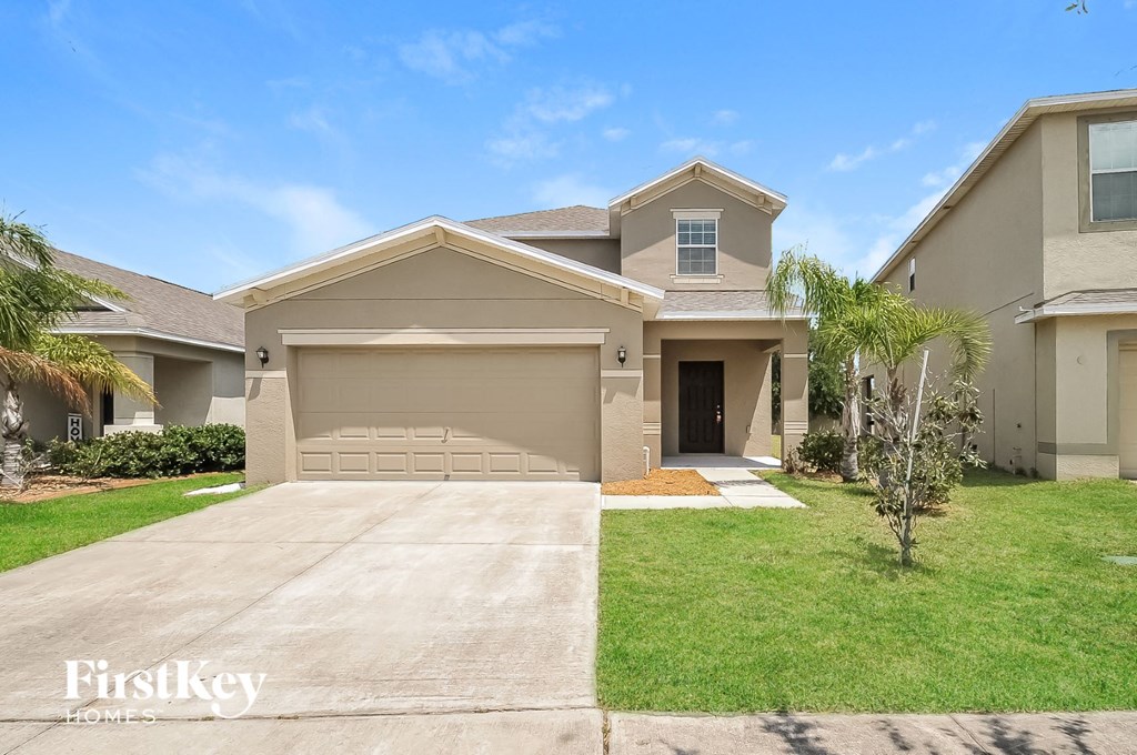 a beige house with a driveway and a palm tree