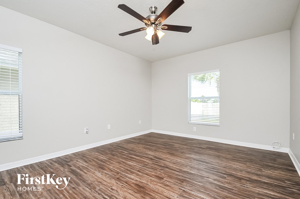 the spacious living room with a ceiling fan and wood flooring