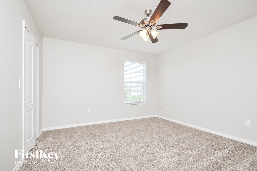 a bedroom with a ceiling fan and a carpeted floor