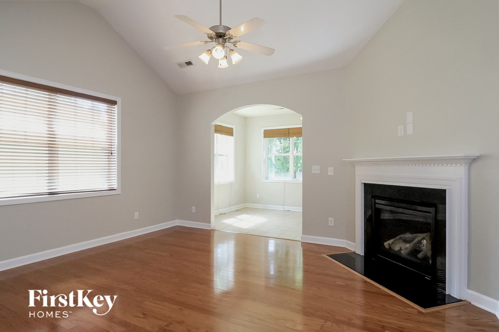 an empty living room with a fireplace and a ceiling fan