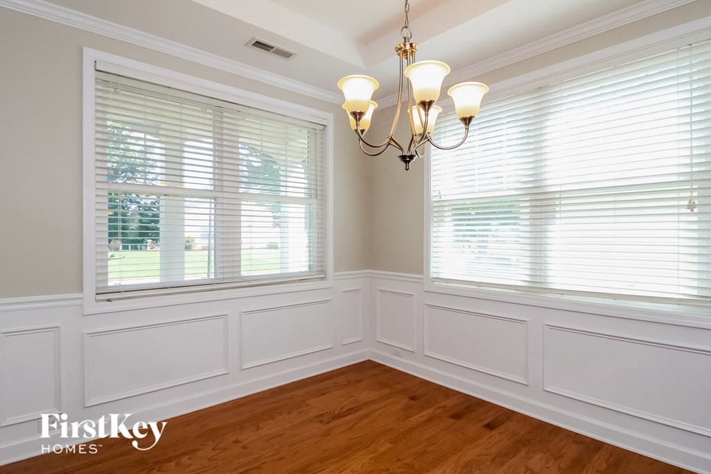 a dining room with two windows and a chandelier