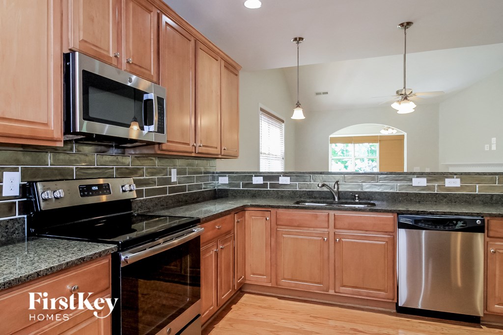 a kitchen with wood cabinets and black countertops and stainless steel appliances