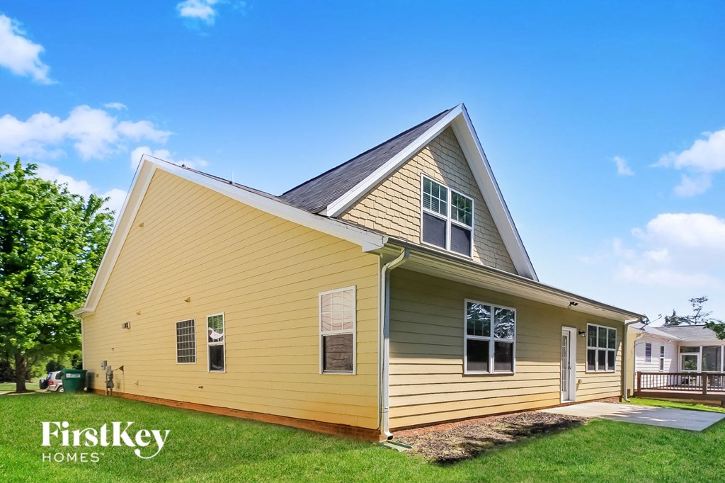 the view of the front of a yellow house with green grass and a blue sky