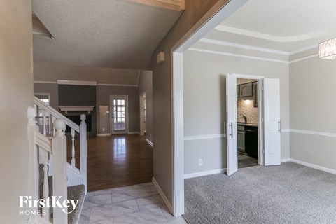 A spacious living room with a television and a staircase leading to the upper floor.