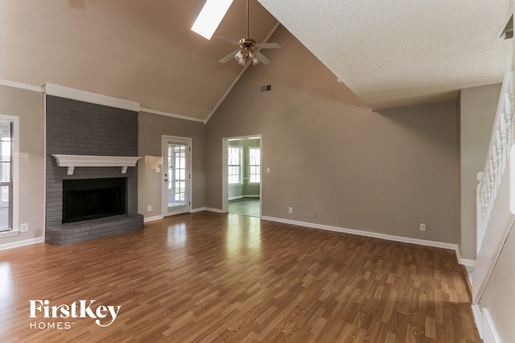 A spacious living room with wood flooring and a fireplace.