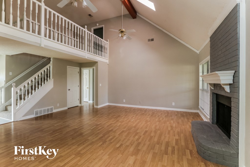 A spacious living room with a fireplace and a staircase.