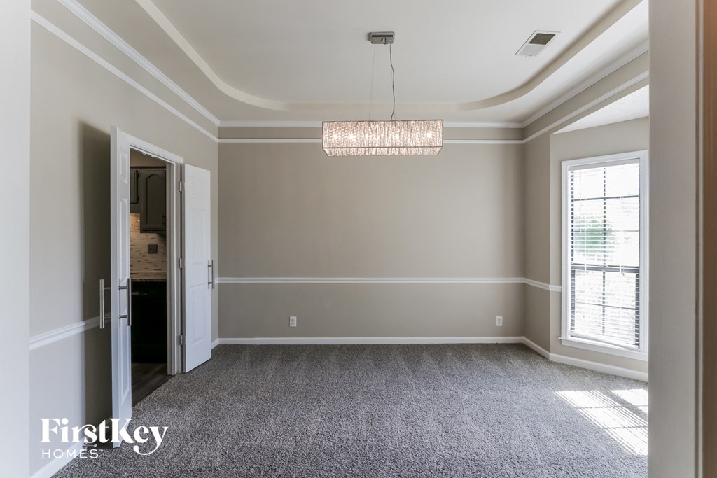 A spacious room with a chandelier hanging from the ceiling.