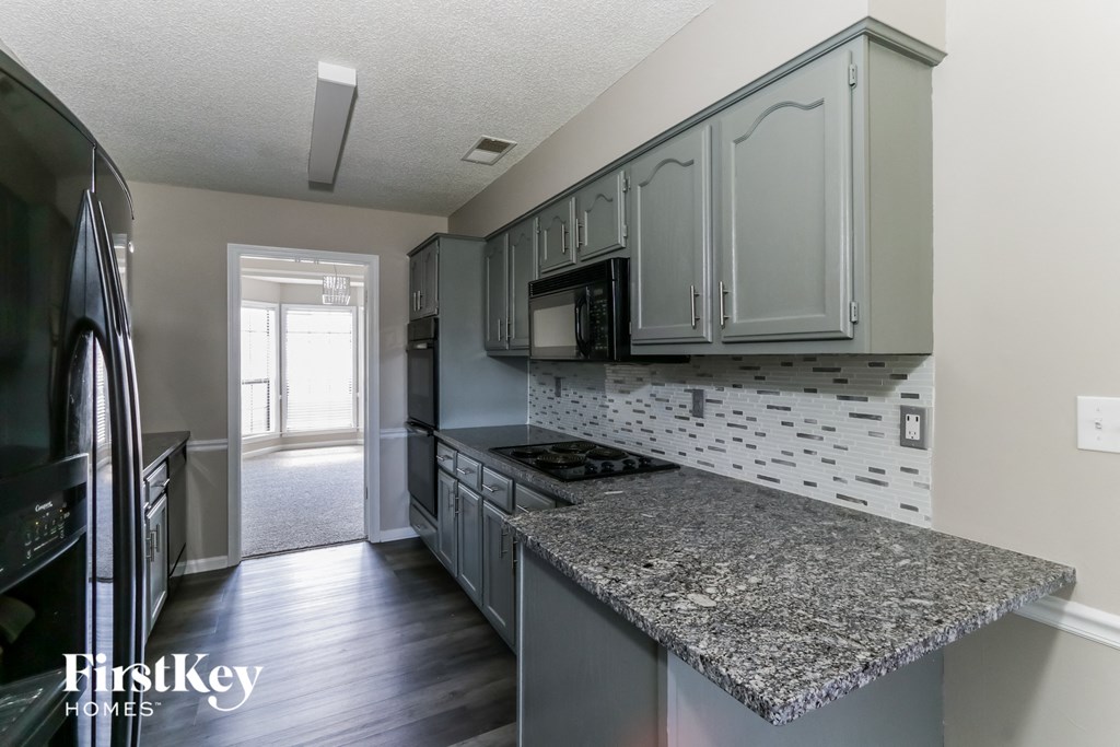 A kitchen with a granite counter top and a stainless steel refrigerator.
