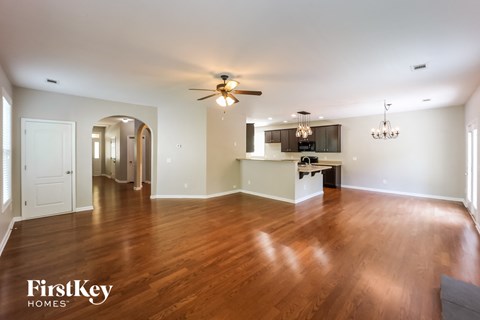 A spacious room with wooden floors and a ceiling fan.