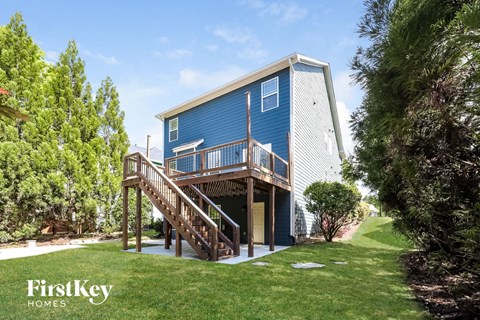 A blue house with a wooden deck and stairs leading to the entrance.