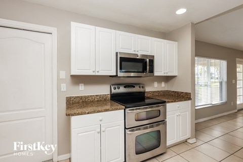 A kitchen with white cabinets and a granite countertop.