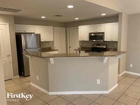 A kitchen with a refrigerator, microwave, and oven.
