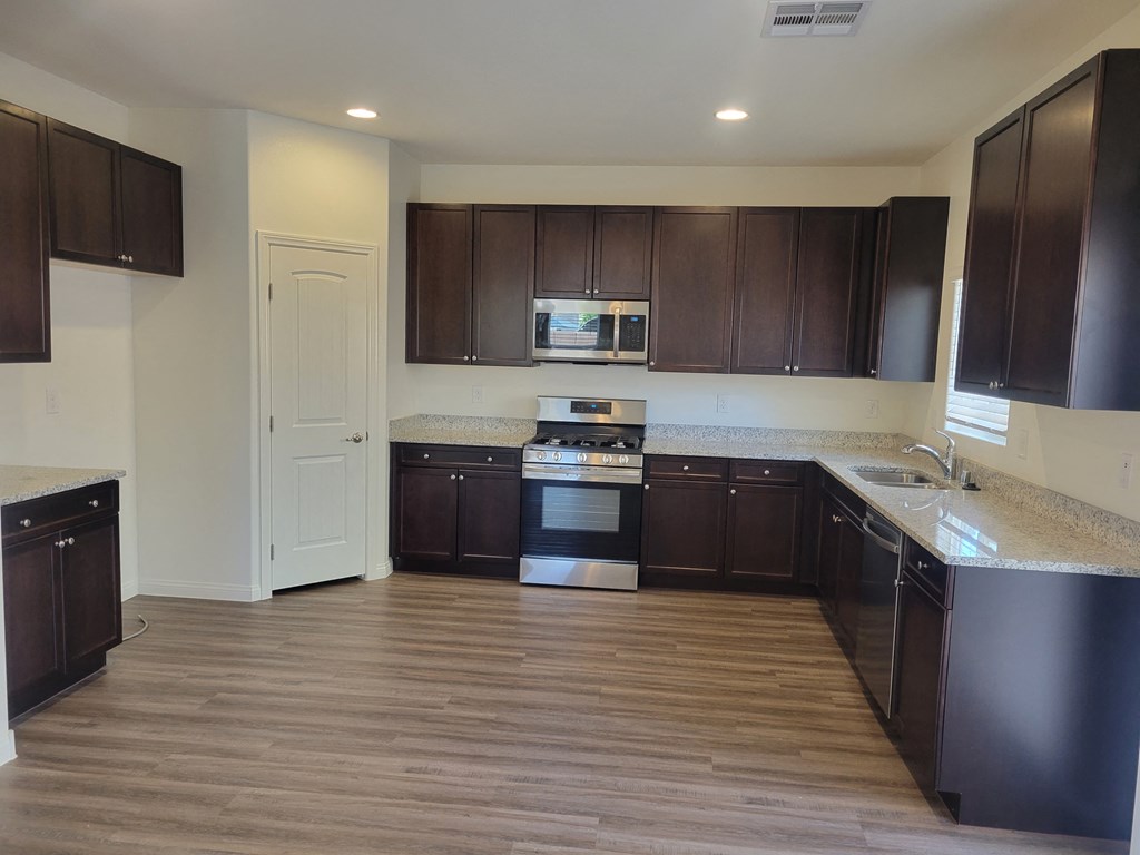 an empty kitchen with dark wood cabinets and stainless steel appliances