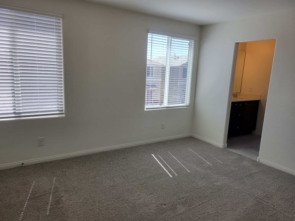 a bedroom with a large window and a carpeted floor