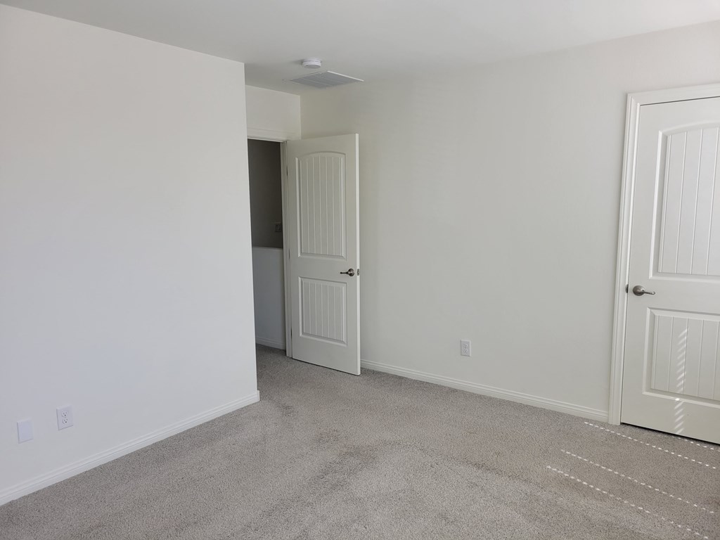 an empty bedroom with white walls and a door to a closet